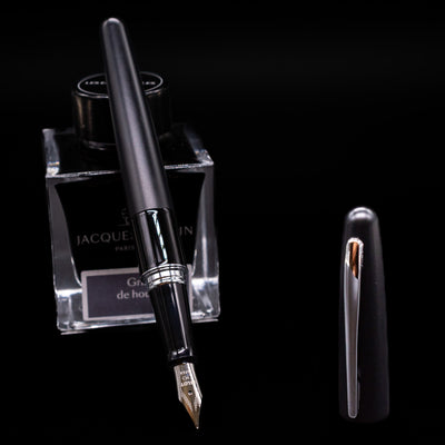 Pilot Metropolitan Fountain Pen - Plain Black leaning on an ink bottle uncapped showcasing the detailing on the nib.