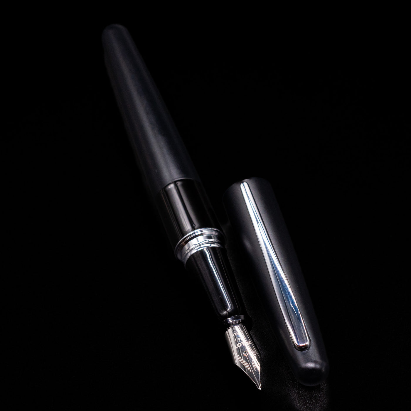 A full view of the Pilot Metropolitan Fountain Pen - Plain Black uncapped, with its cap laying next to the pen. 