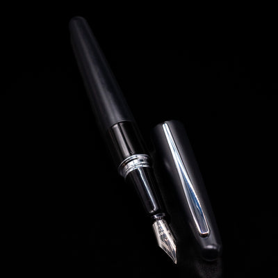 A full view of the Pilot Metropolitan Fountain Pen - Plain Black uncapped, with its cap laying next to the pen. 