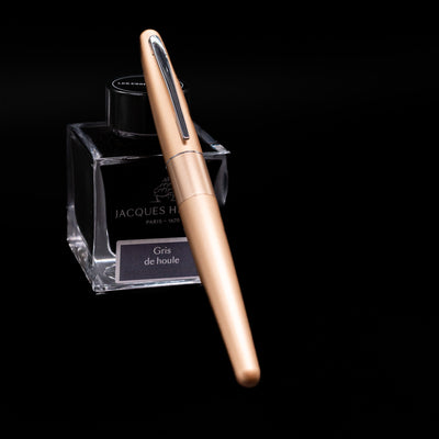 Pilot Metropolitan Fountain Pen - Plain Gold capped, leaning against an ink bottle. 