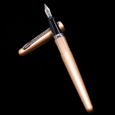 Pilot Metropolitan Fountain Pen - Plain Gold laying on top of its cap in a crossed position showing full view of the entire uncapped pen.