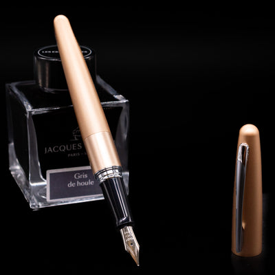Pilot Metropolitan Fountain Pen - Plain Gold leaning on an ink bottle uncapped showcasing the detailing on the nib.