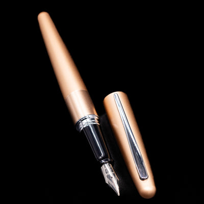 A full view of the Pilot Metropolitan Fountain Pen - Plain Gold uncapped, with its cap laying next to the pen. 