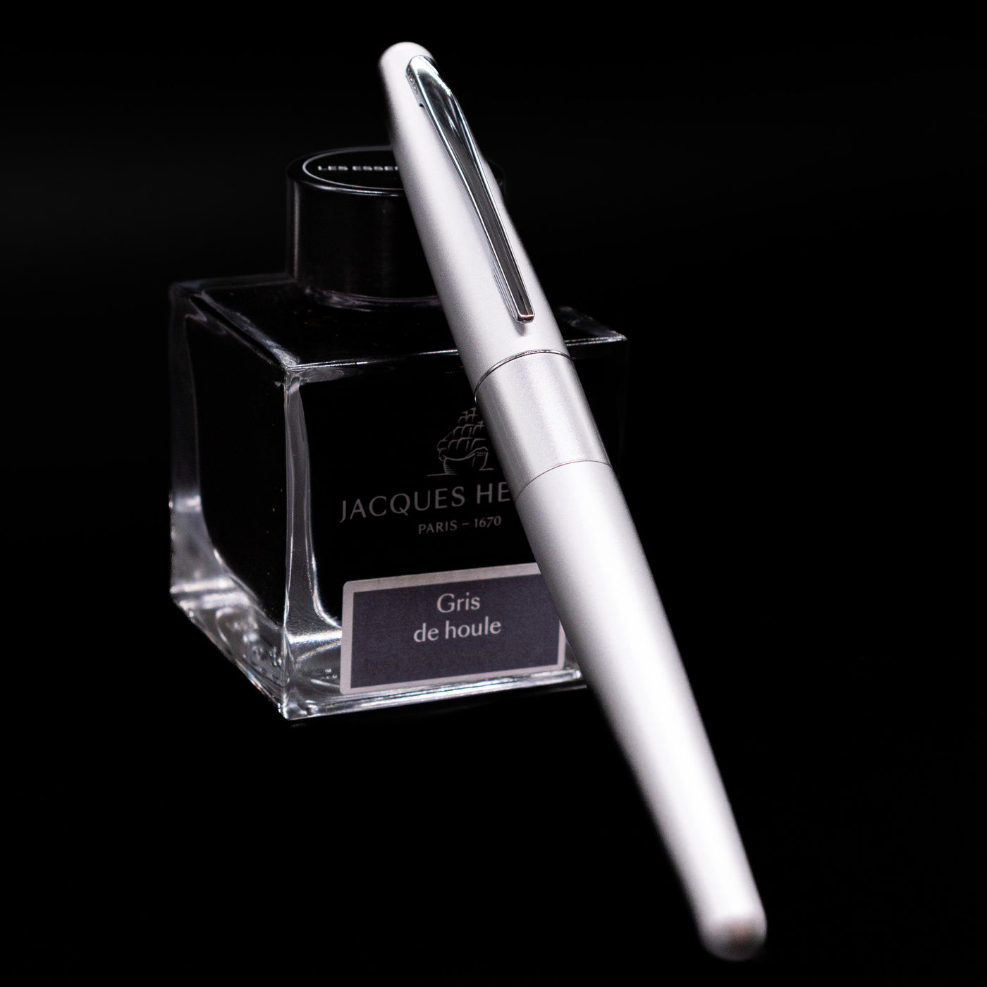 Pilot Metropolitan Fountain Pen - Plain Silver capped, leaning against an ink bottle. 