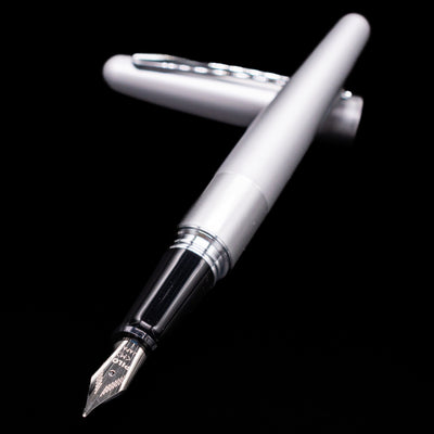 Pilot Metropolitan Fountain Pen - Plain Silver laying across its own cap, crossed, with a focus on the nib.