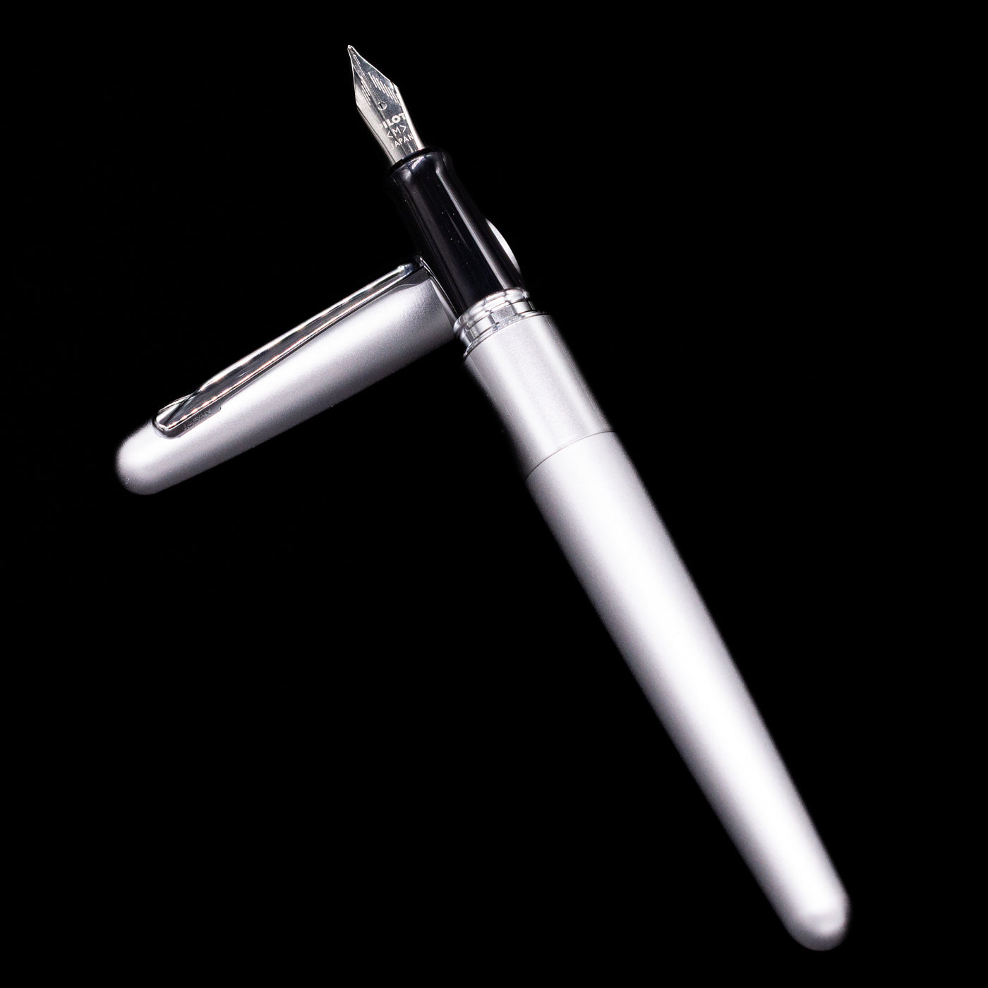 Pilot Metropolitan Fountain Pen - Plain Silver laying on top of its cap in a crossed position showing full view of the entire uncapped pen.