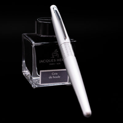 Pilot Metropolitan Fountain Pen - Silver with Dots capped, leaning against an ink bottle. 