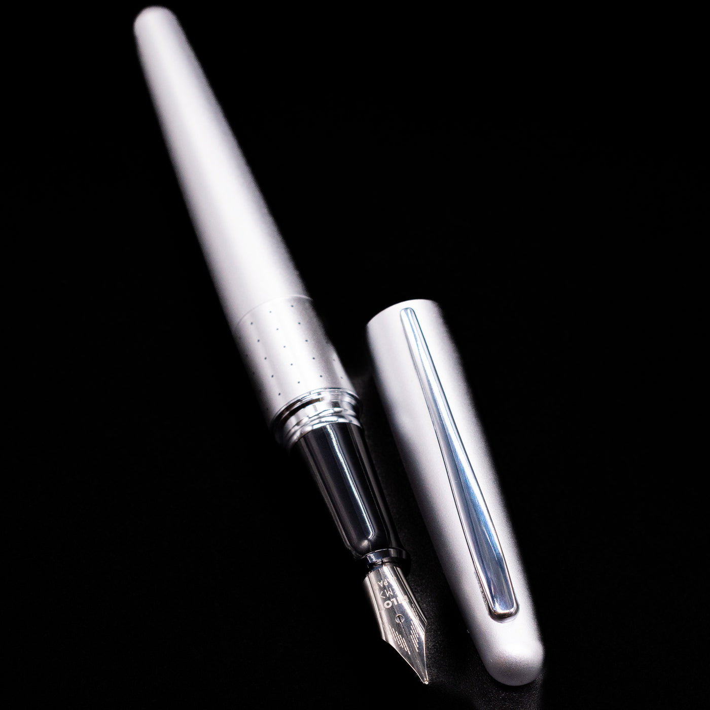 A full view of the Pilot Metropolitan Fountain Pen - Silver with Dots uncapped, with its cap laying next to the pen. 