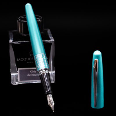 Pilot Metropolitan MR Retro Pop Fountain Pen - Turquoise leaning on an ink bottle uncapped showcasing the detailing on the nib.