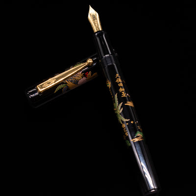Pilot Namiki Sokuikinen HouOu (Double Phoenix) Maki-e Fountain Pen by Kyusai Yoshida - Preowned laying on top of its cap in a crossed position showing full view of the entire uncapped pen.