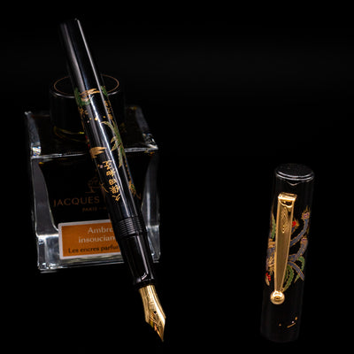 Pilot Namiki Sokuikinen HouOu (Double Phoenix) Maki-e Fountain Pen by Kyusai Yoshida - Preowned leaning on an ink bottle uncapped showcasing the detailing on the nib.