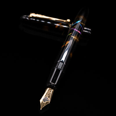 Pilot Namiki Yukari Maki-e Fountain Pen - Firefly laying across its own cap, crossed, with a focus on the nib.