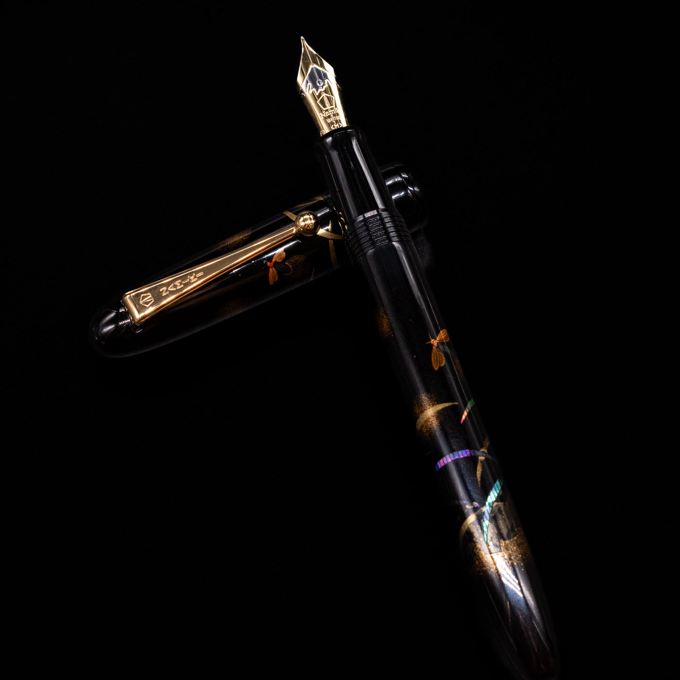 Pilot Namiki Yukari Maki-e Fountain Pen - Firefly laying on top of its cap in a crossed position showing full view of the entire uncapped pen.