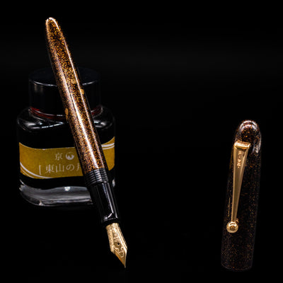 Pilot Namiki Yukari Maki-e Fountain Pen - Sakura Fubuki leaning on an ink bottle uncapped showcasing the detailing on the nib.