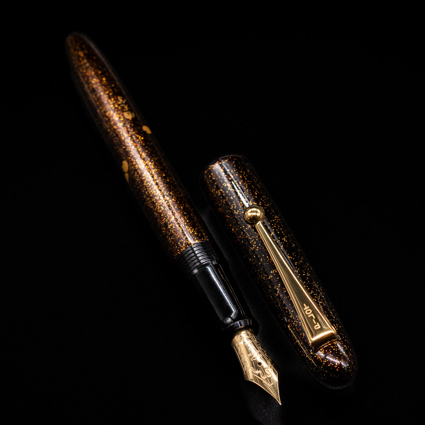  A full view of the Pilot Namiki Yukari Maki-e Fountain Pen - Sakura Fubuki uncapped, with its cap laying next to the pen. 