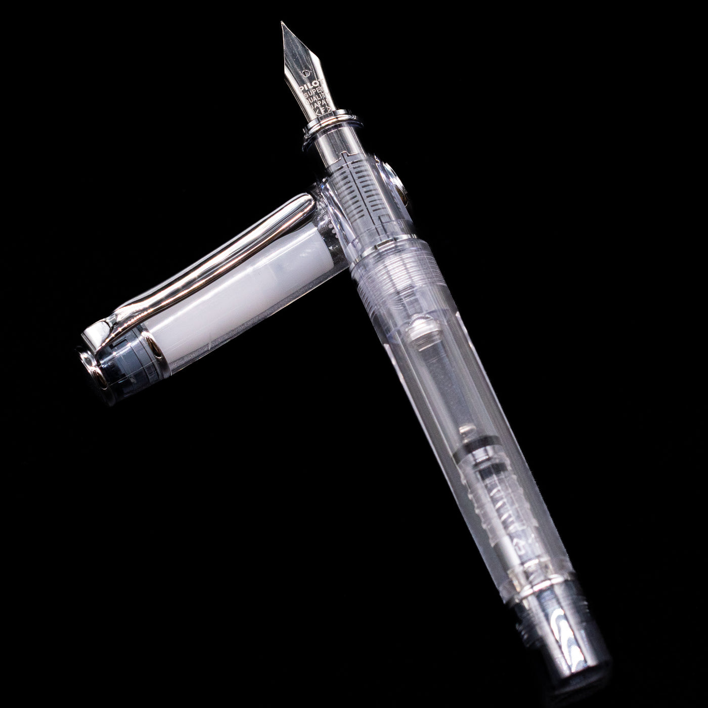 Pilot Prera Fountain Pen - Black laying on top of its cap in a crossed position showing full view of the entire uncapped pen.