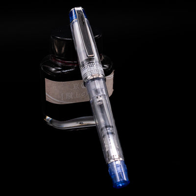 Pilot Prera Fountain Pen - Blue capped, leaning against an ink bottle. 