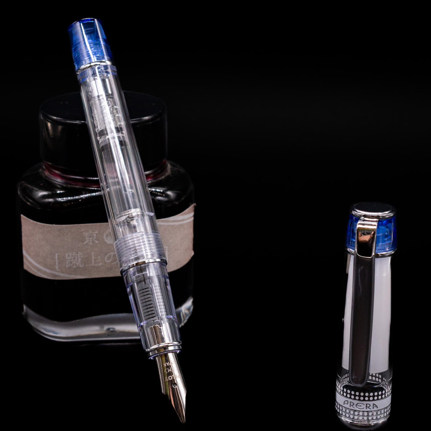 Pilot Prera Fountain Pen - Blue leaning on an ink bottle uncapped showcasing the detailing on the nib.