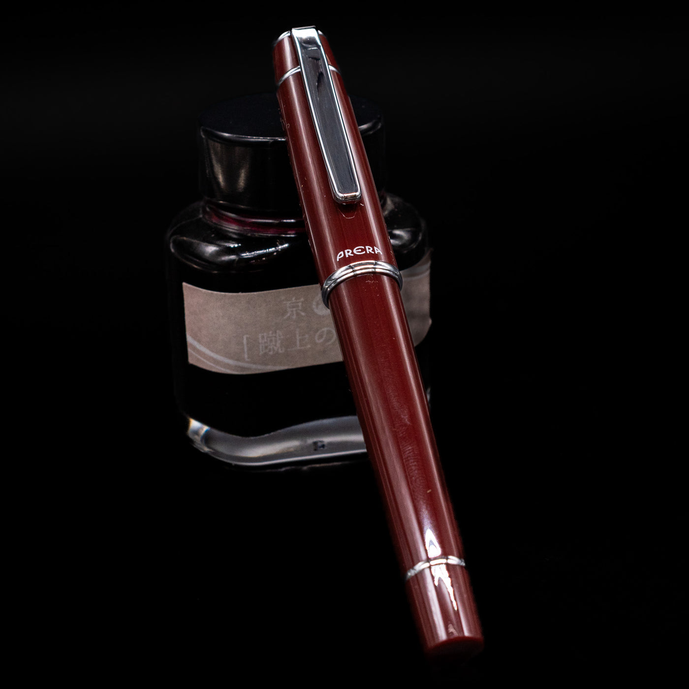 Pilot Prera Fountain Pen - Cinnamon Brown capped, leaning against an ink bottle. 