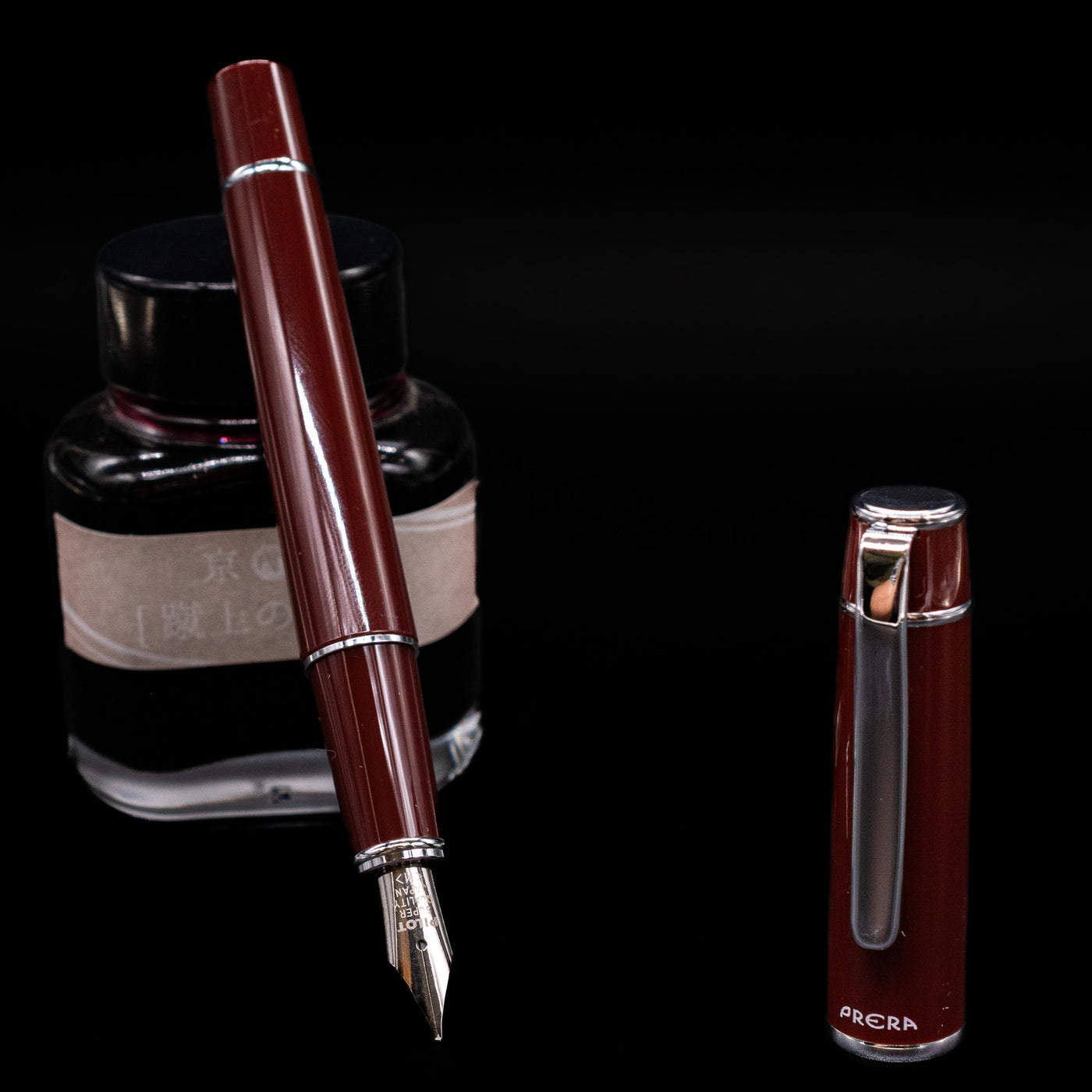 Pilot Prera Fountain Pen - Cinnamon Brown leaning on an ink bottle uncapped showcasing the detailing on the nib.