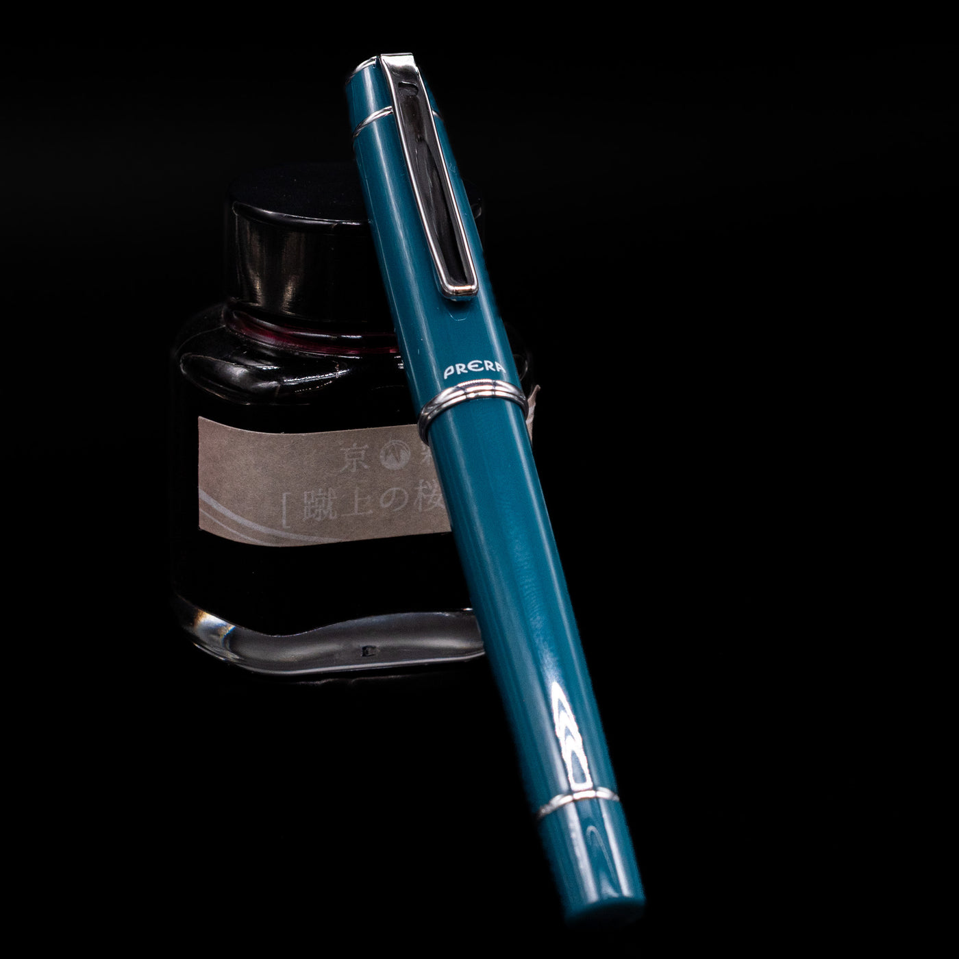 Pilot Prera Fountain Pen - Empress Teal capped, leaning against an ink bottle. 