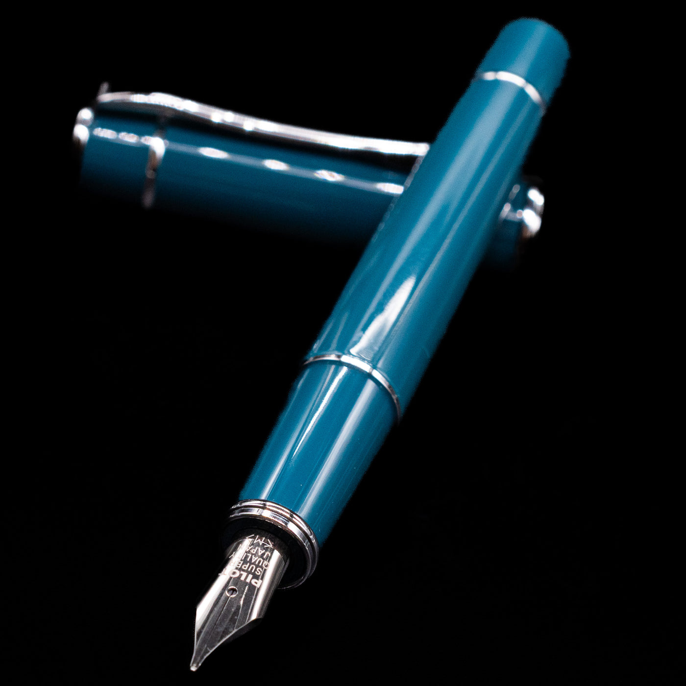 Pilot Prera Fountain Pen - Empress Teal laying across its own cap, crossed, with a focus on the nib.