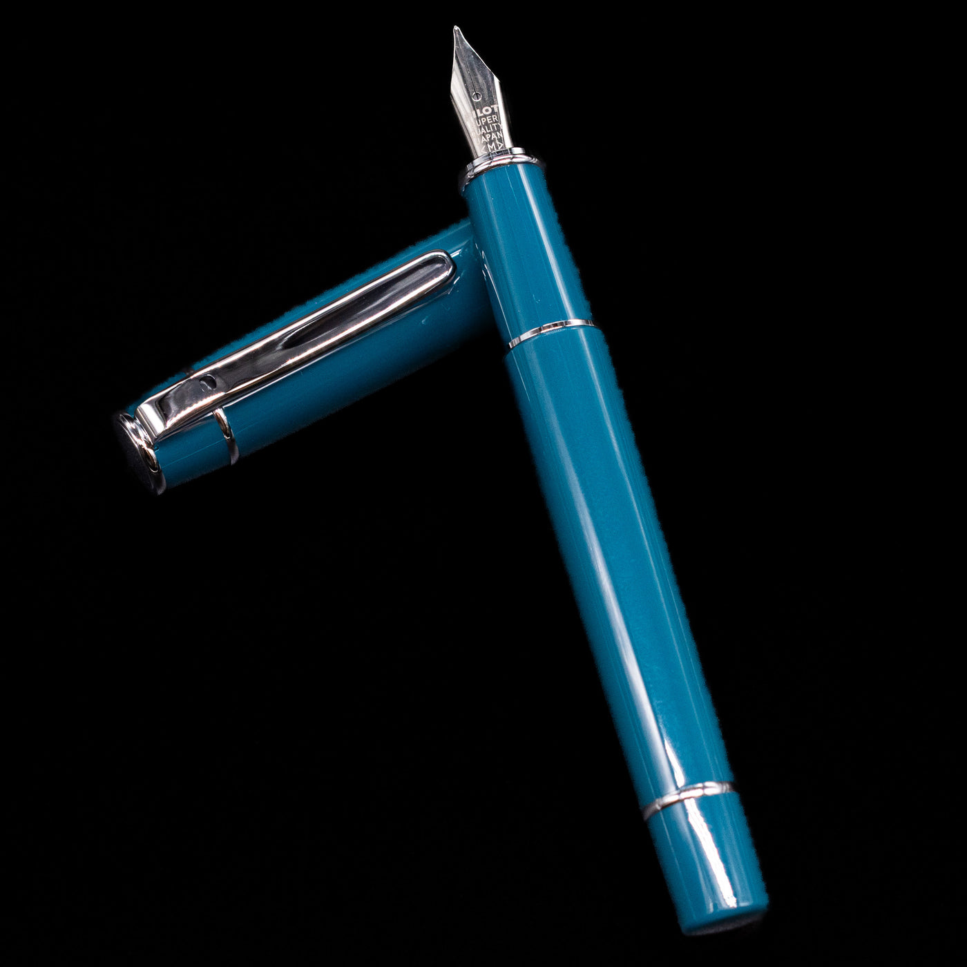 Pilot Prera Fountain Pen - Empress Teal laying on top of its cap in a crossed position showing full view of the entire uncapped pen.