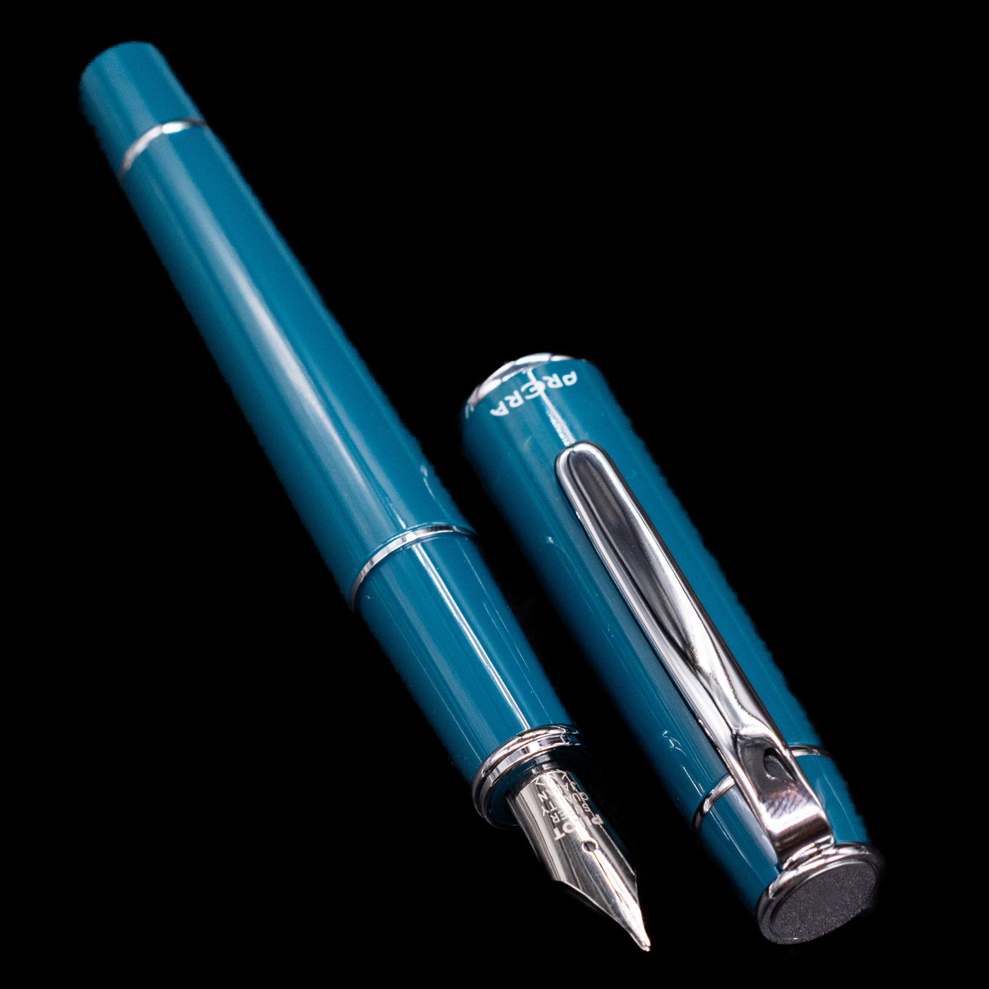  A full view of the Pilot Prera Fountain Pen - Empress Teal uncapped, with its cap laying next to the pen. 