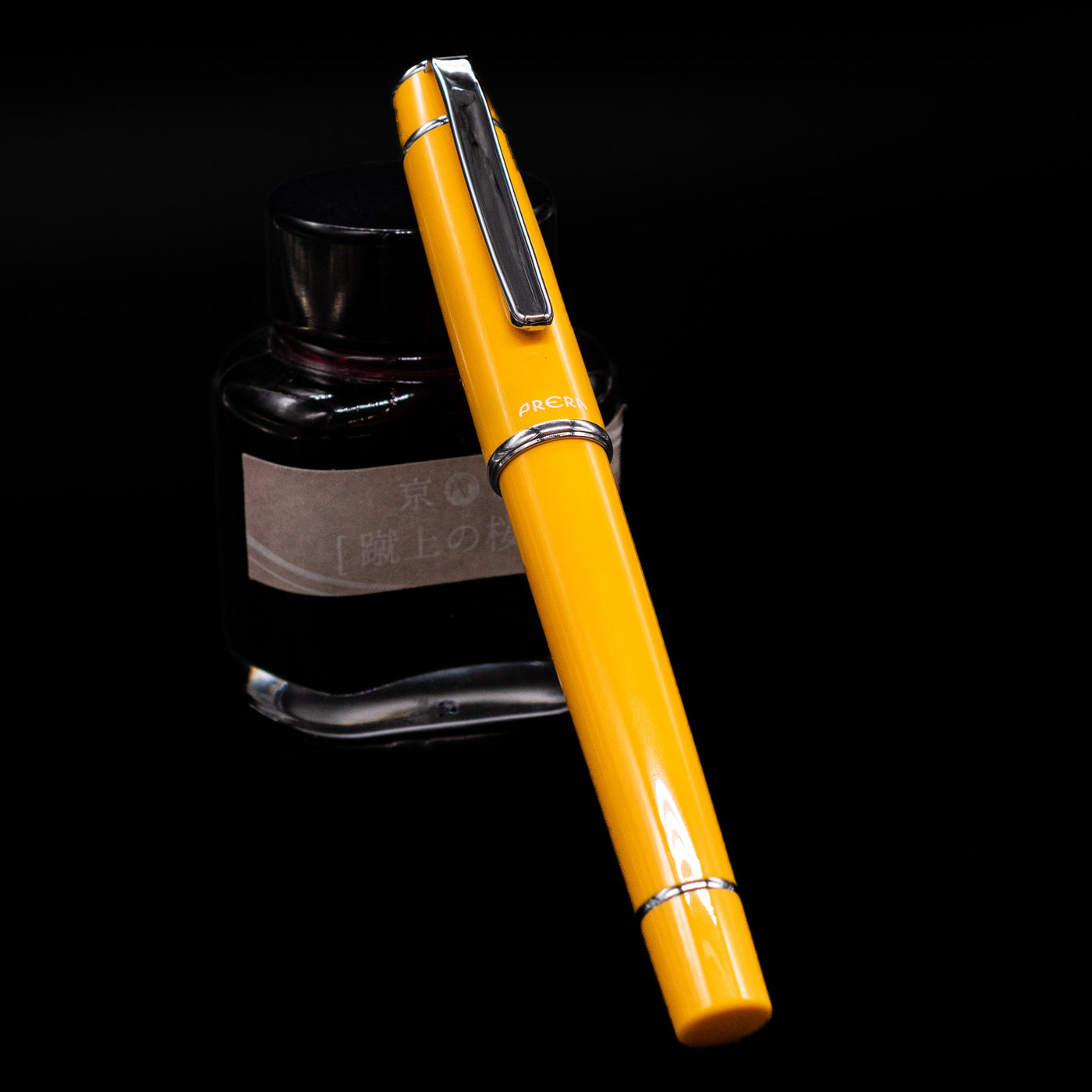 Pilot Prera Fountain Pen - Honey Yellow capped, leaning against an ink bottle. 