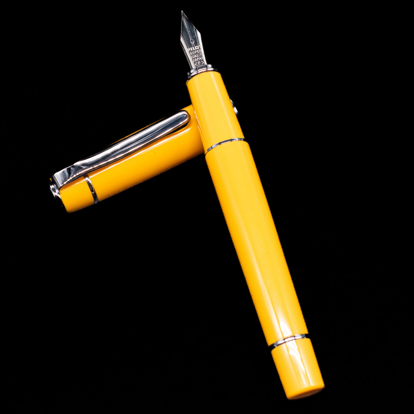 Pilot Prera Fountain Pen - Honey Yellow laying on top of its cap in a crossed position showing full view of the entire uncapped pen.