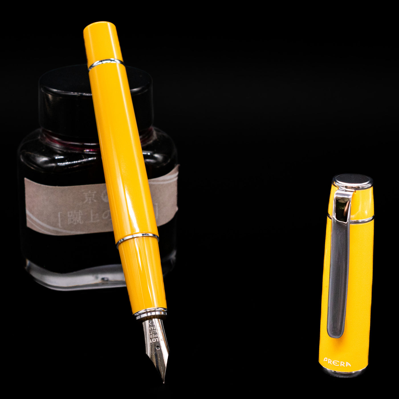 Pilot Prera Fountain Pen - Honey Yellow leaning on an ink bottle uncapped showcasing the detailing on the nib.