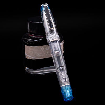Pilot Prera Fountain Pen - Light Blue capped, leaning against an ink bottle. 