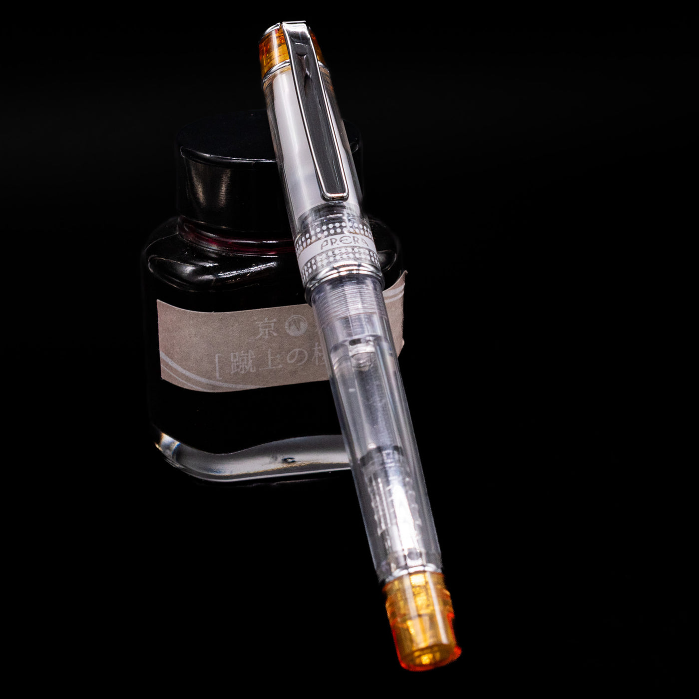 Pilot Prera Fountain Pen - Orange capped, leaning against an ink bottle. 