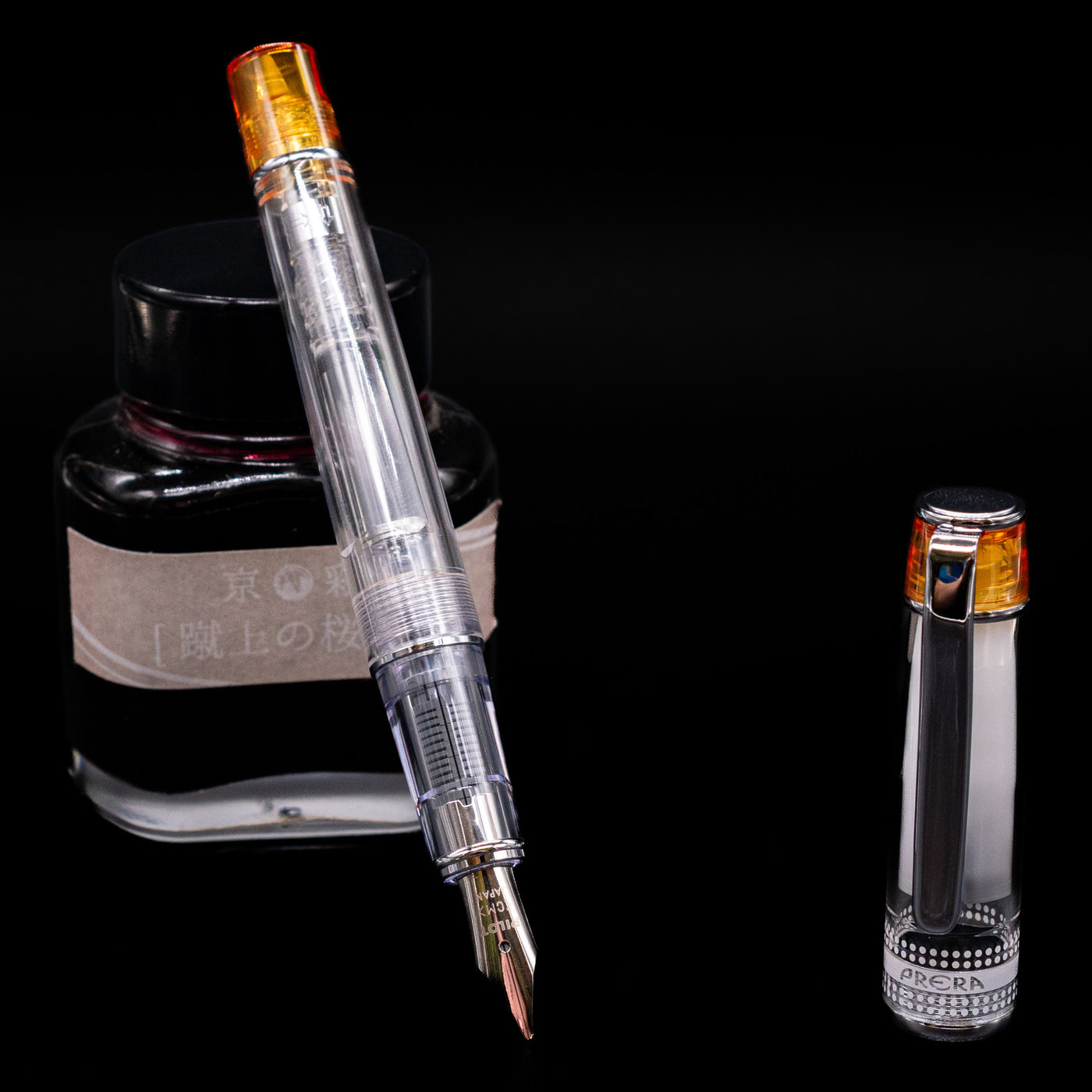 Pilot Prera Fountain Pen - Orange leaning on an ink bottle uncapped showcasing the detailing on the nib.