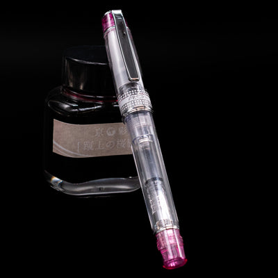Pilot Prera Fountain Pen - Pink capped, leaning against an ink bottle. 