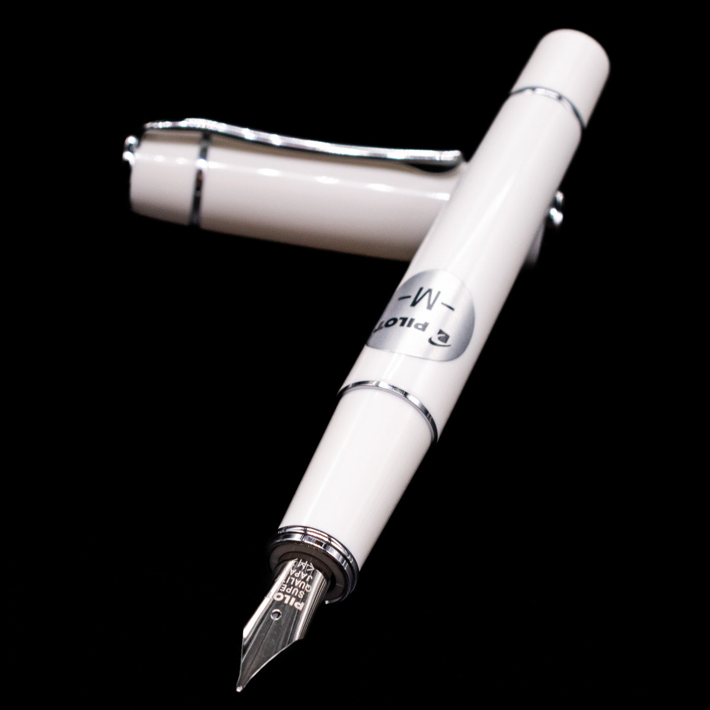 Pilot Prera Fountain Pen - Porcelain White laying across its own cap, crossed, with a focus on the nib.