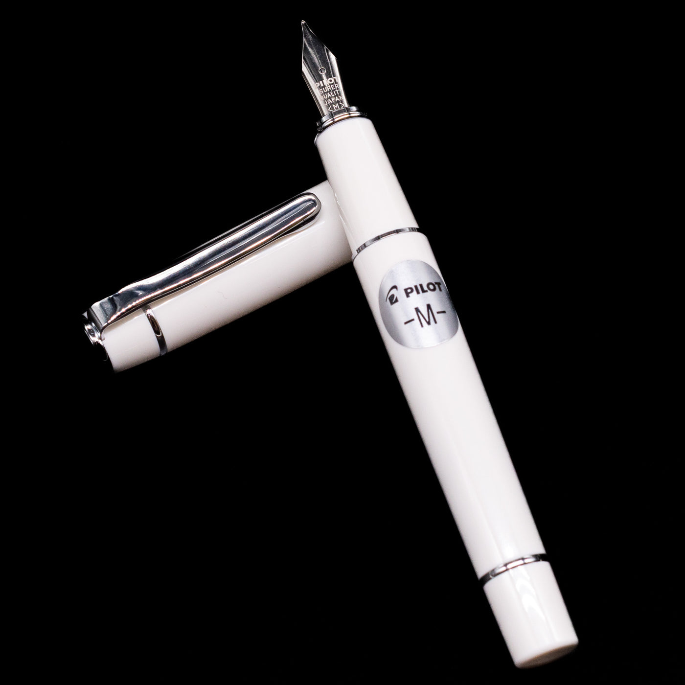 Pilot Prera Fountain Pen - Porcelain White laying on top of its cap in a crossed position showing full view of the entire uncapped pen.