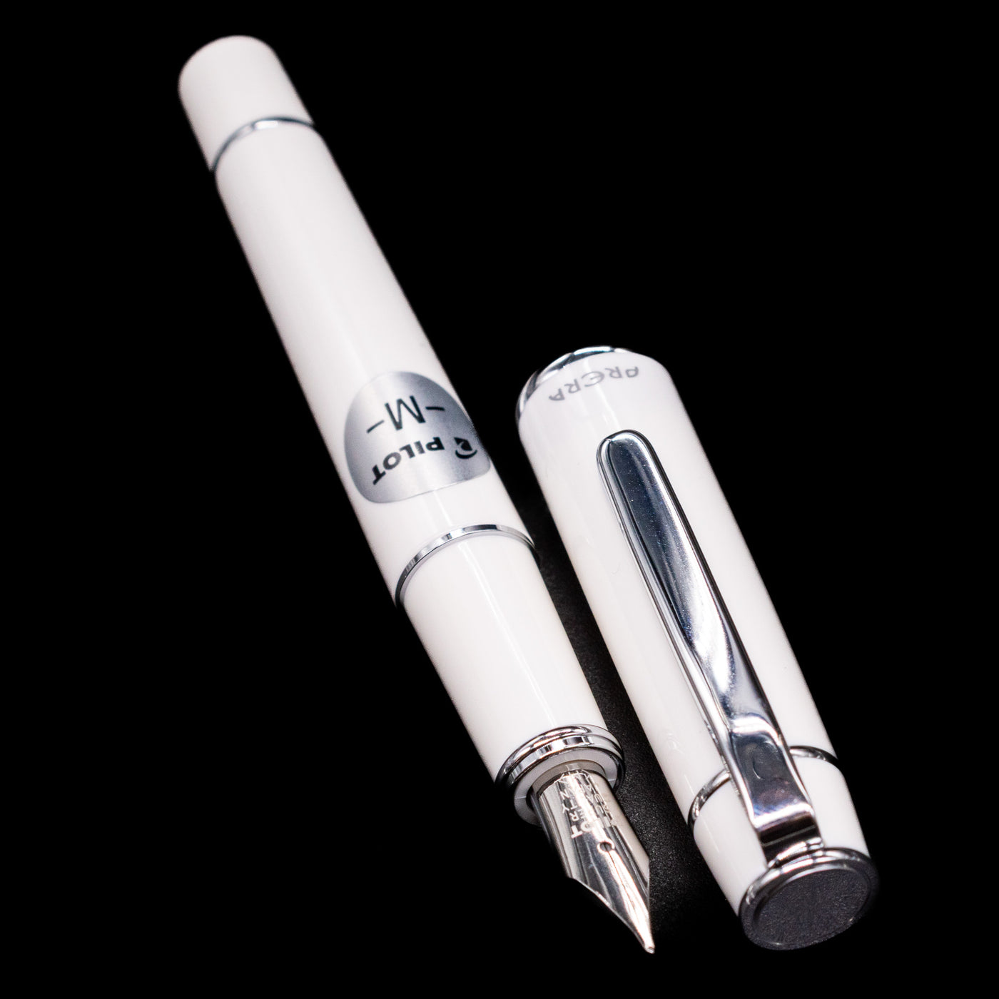 A full view of the Pilot Prera Fountain Pen - Porcelain White uncapped, with its cap laying next to the pen. 