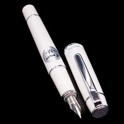 A full view of the Pilot Prera Fountain Pen - Porcelain White uncapped, with its cap laying next to the pen. 