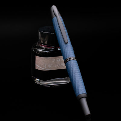Pilot Vanishing Point Limited Edition 2025 Fountain Pen - Midnight Link leaning on an ink bottle with the nib retracted.
