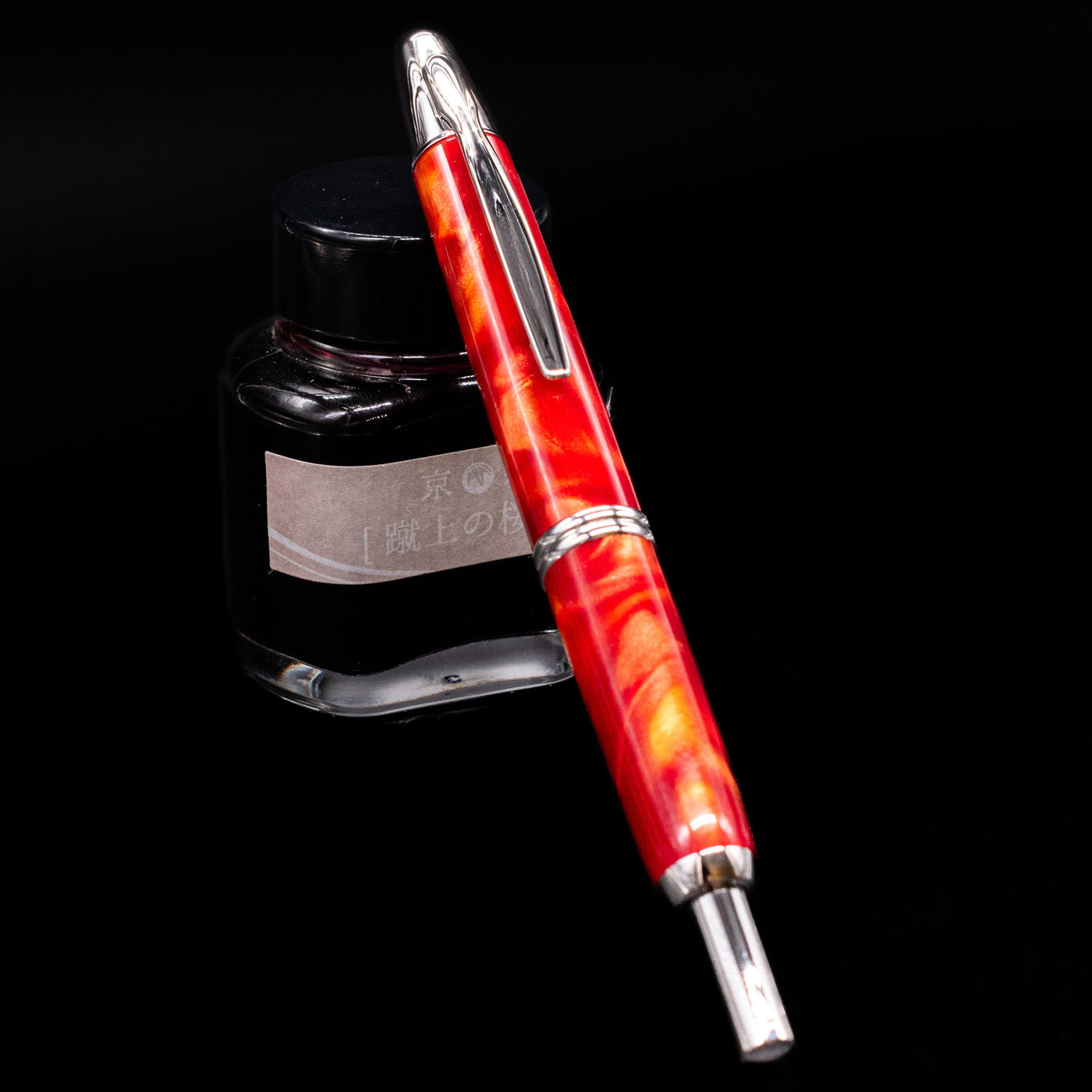 Pilot Vanishing Point SE Fountain Pen - Marble Orange capped, leaning against an ink bottle.
