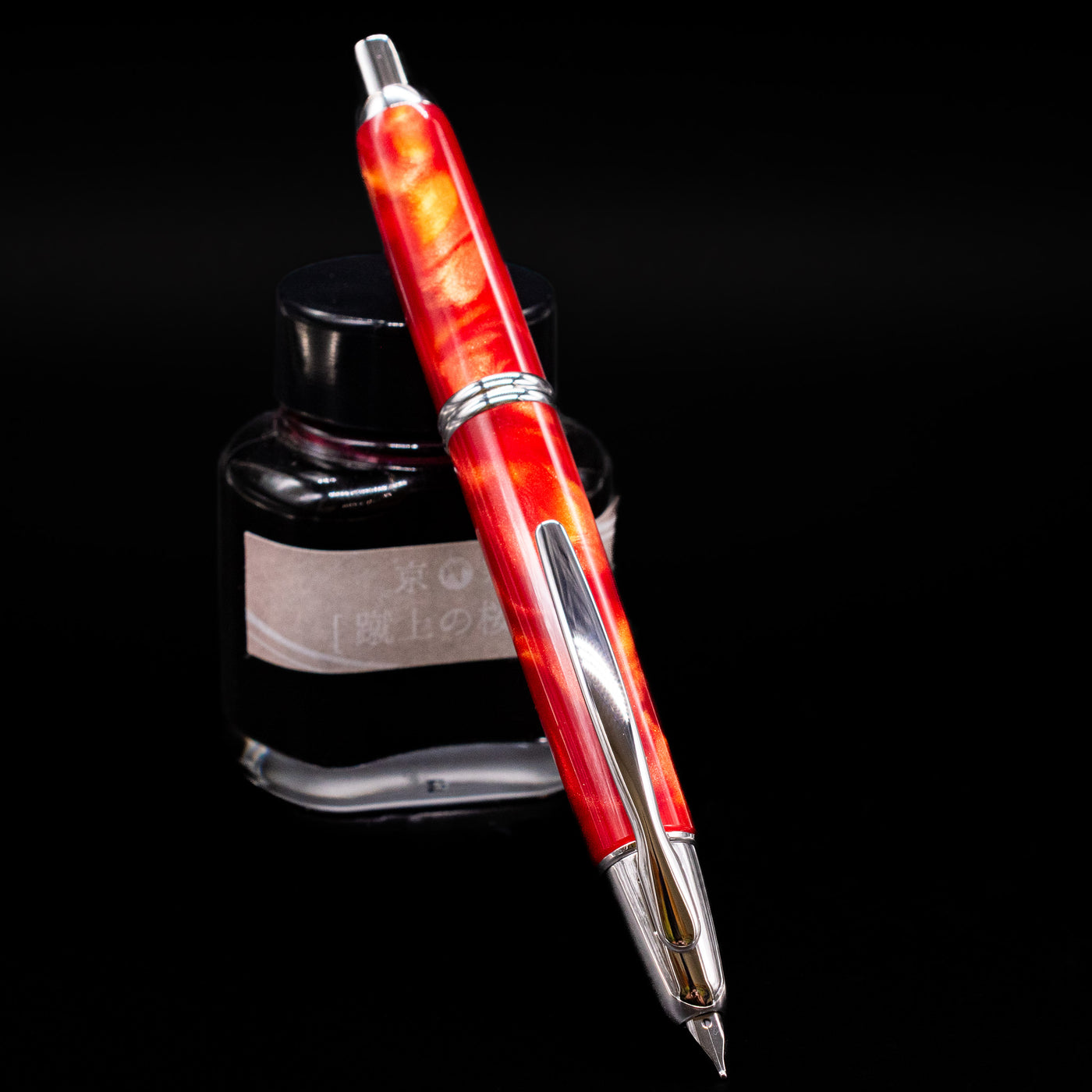 Pilot Vanishing Point SE Fountain Pen - Marble Orange leaning against an ink bottle activated.