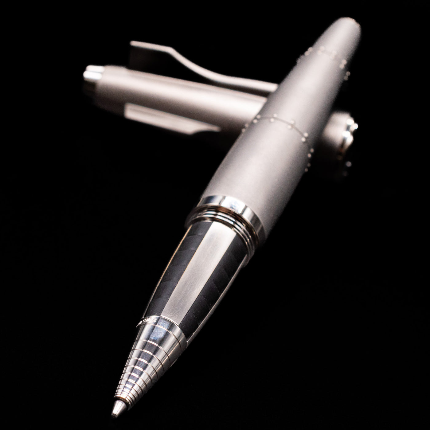 Romain Jerome Moon Fighter Rollerball Pen - Heavy Metal laying across its own cap, crossed, with a focus on the tip.