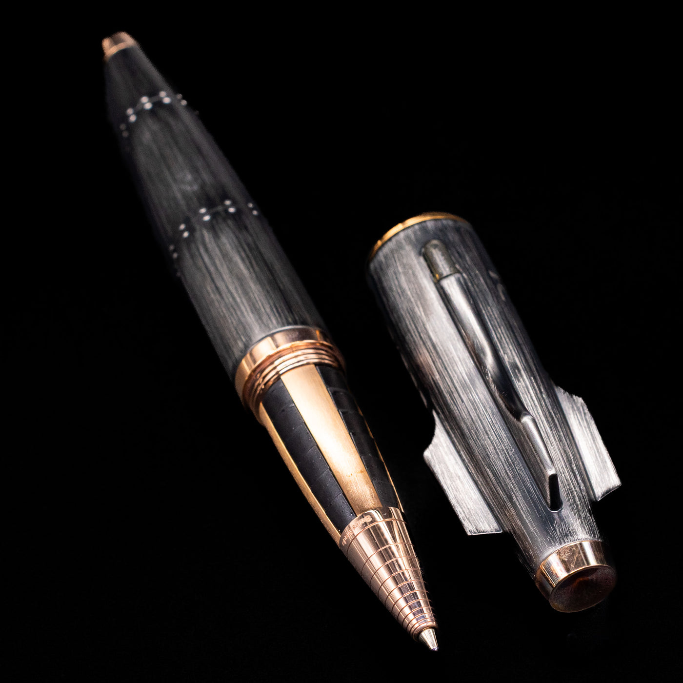 A full view of the Romain Jerome Moon Fighter Rollerball Pen - Vintage Finish uncapped, with its cap laying next to the pen. 