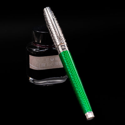 ST Dupont Line D Eternity Snake Skin Fountain Pen - Green capped, leaning against an ink bottle. 