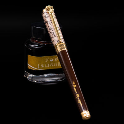 ST Dupont William Shakespeare Rollerball Pen - Preowned capped, leaning against an ink bottle. 