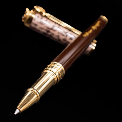 ST Dupont William Shakespeare Rollerball Pen - Preowned laying across its own cap, crossed, with a focus on the tip.