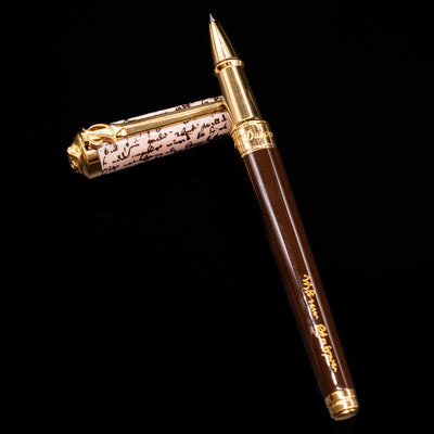 ST Dupont William Shakespeare Rollerball Pen - Preowned laying on top of its cap in a crossed position showing full view of the entire uncapped pen.