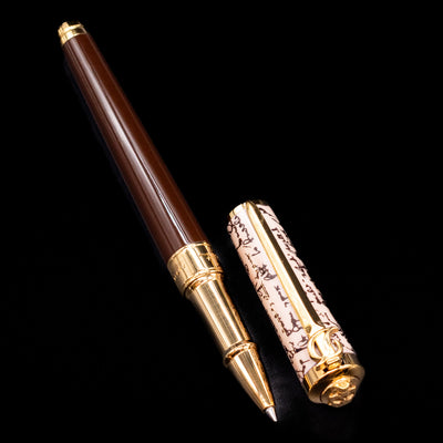 A full view of the ST Dupont William Shakespeare Rollerball Pen - Preowned  uncapped, with its cap laying next to the pen. 