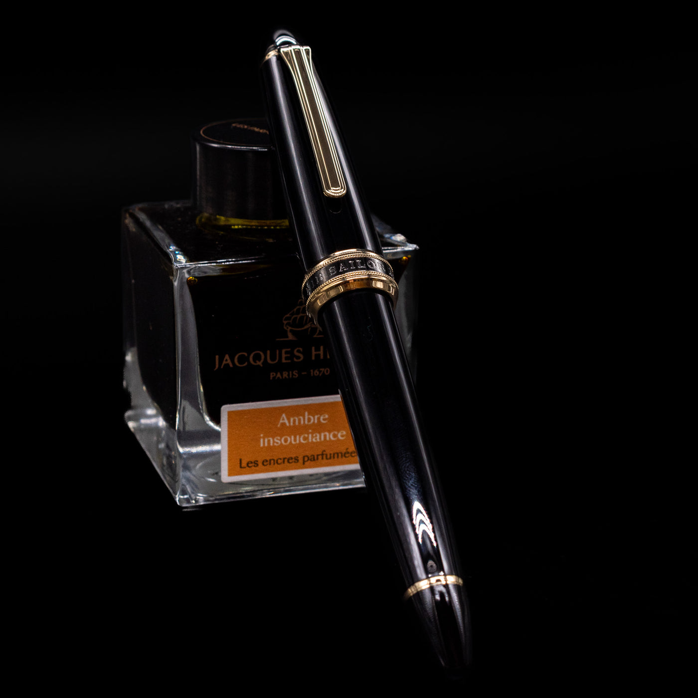 Sailor 1911L Fountain Pen - Black / King Eagle Nib capped, leaning against an ink bottle. 